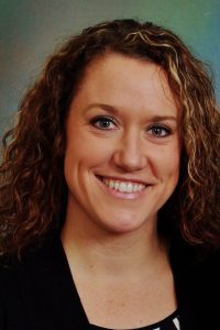 A woman with curly hair smiling at the camera.