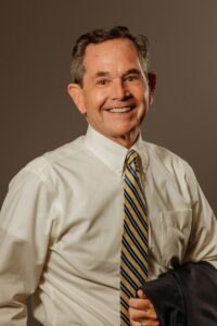 A man with a friendly smile wearing a striped tie, looking directly at the camera. Rod Rowan